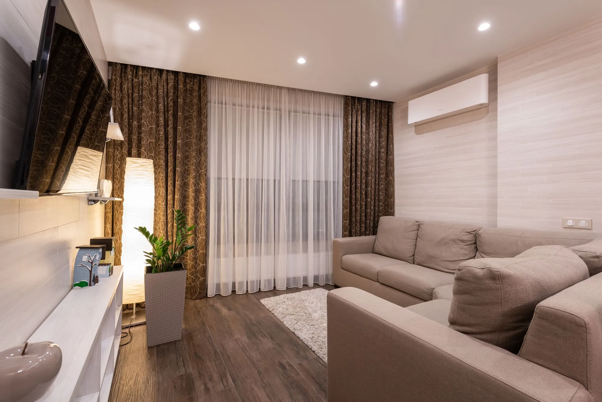 Bright, spotless living room with a cream sofa, hardwood floor and sheer curtains