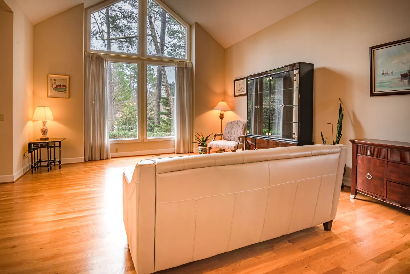 Tidy living room with a leather sofa, polished hardwood floor and tall windows letting in daylight